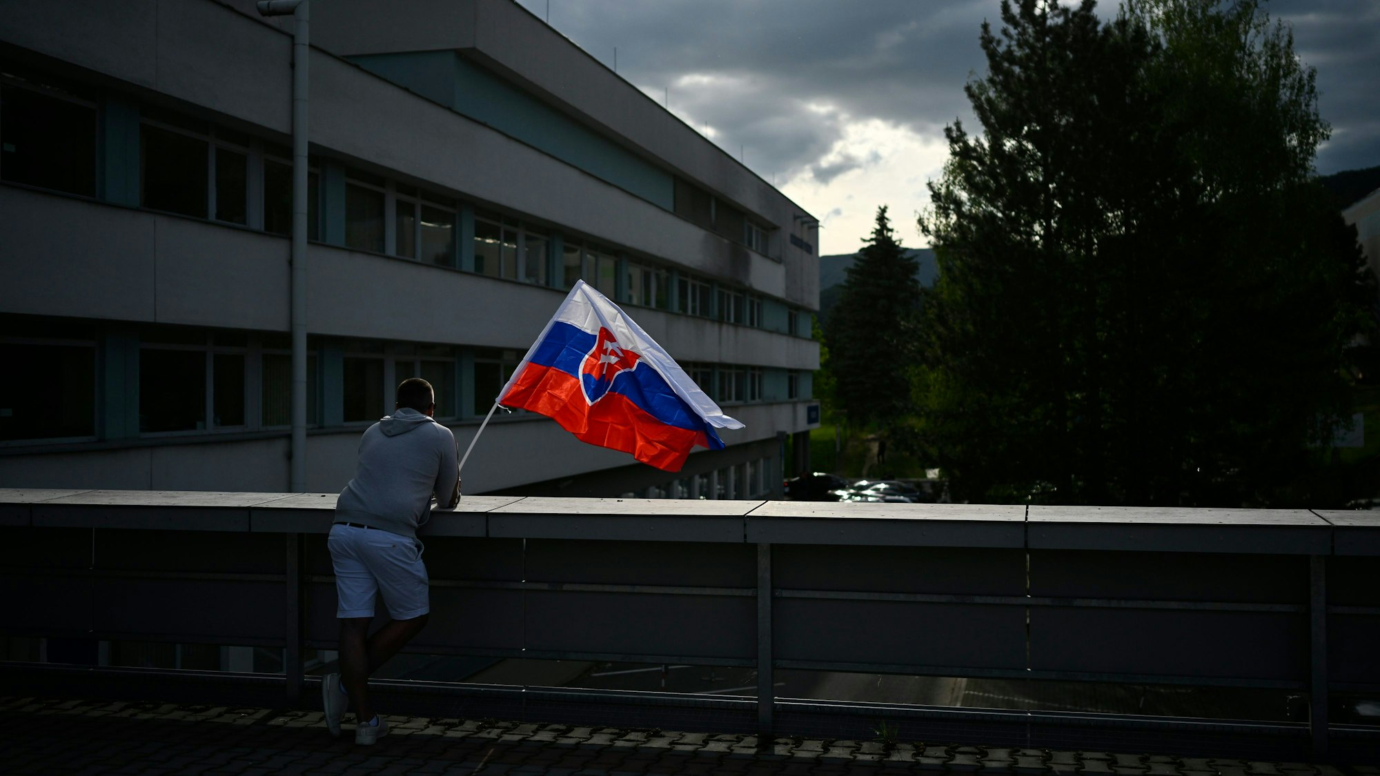 Ein Mann steht mit der slowakischen Flagge am F. D. Roosevelt Universitätskrankenhaus in Banska Bystrica, wo Robert Fico auf der Intensivstation liegt.