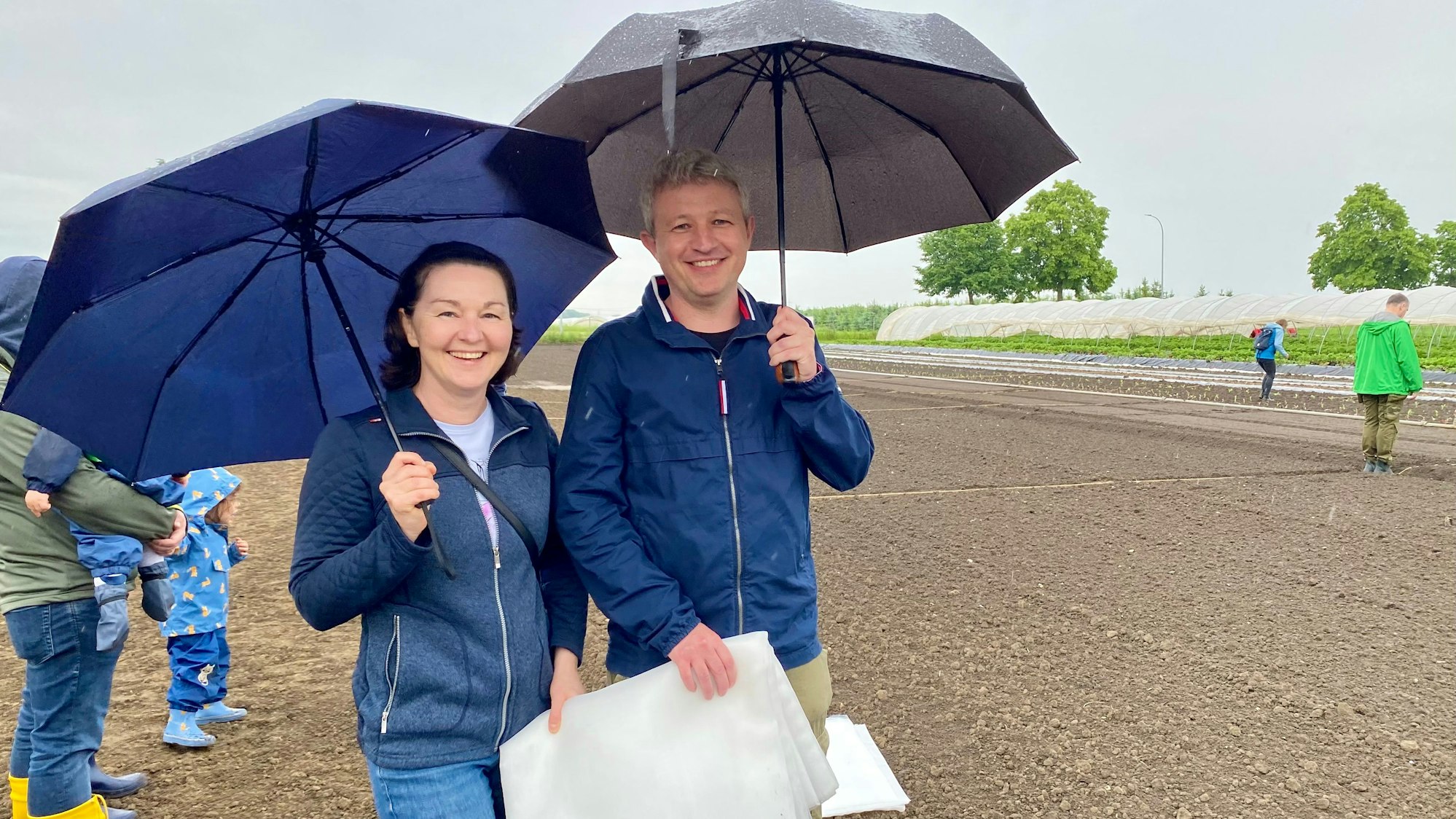 Zu sehen sind Agnieszka und Stefan Lupuliev, die Regenschirme in der Hand halten.