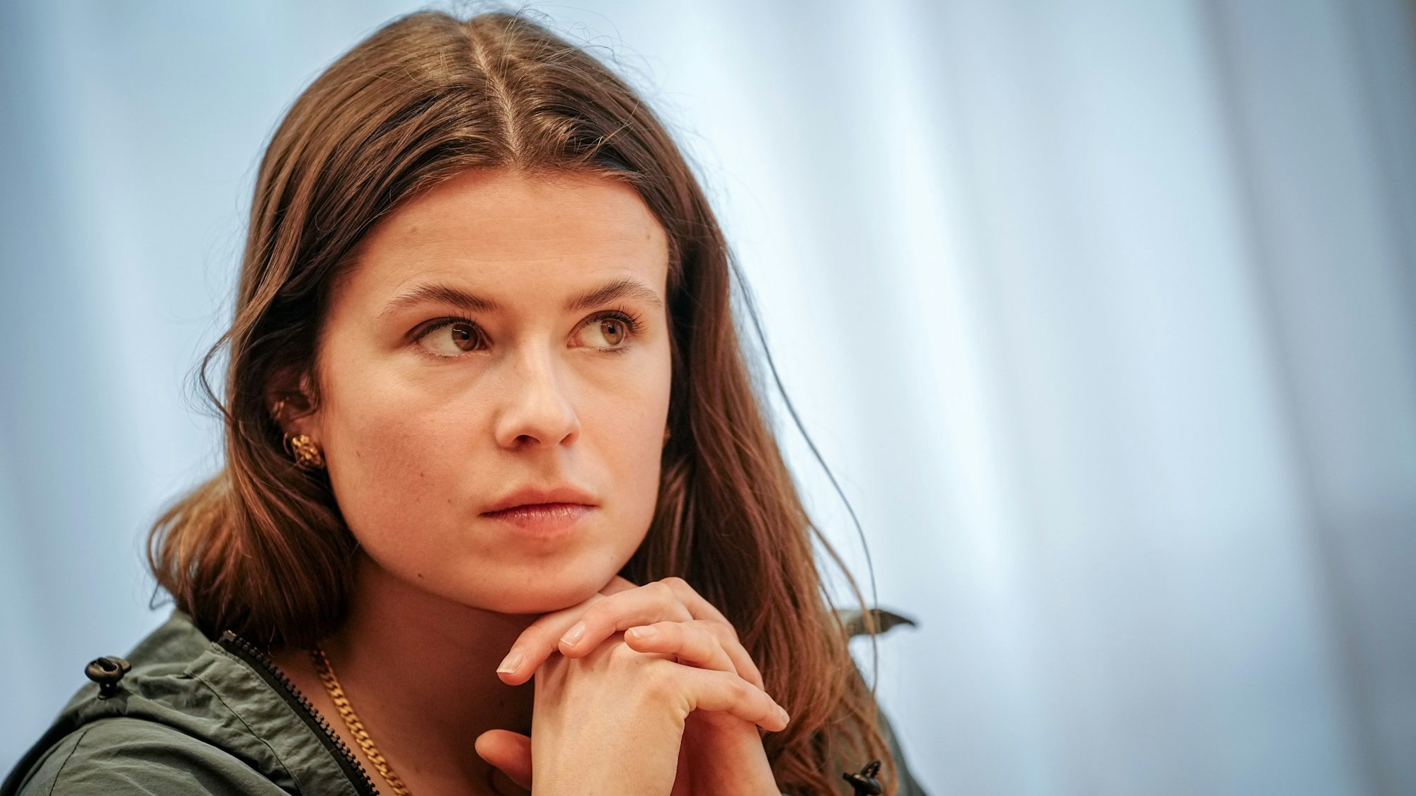 Luisa Neubauer faltet die Hände unter ihrem Kinn.