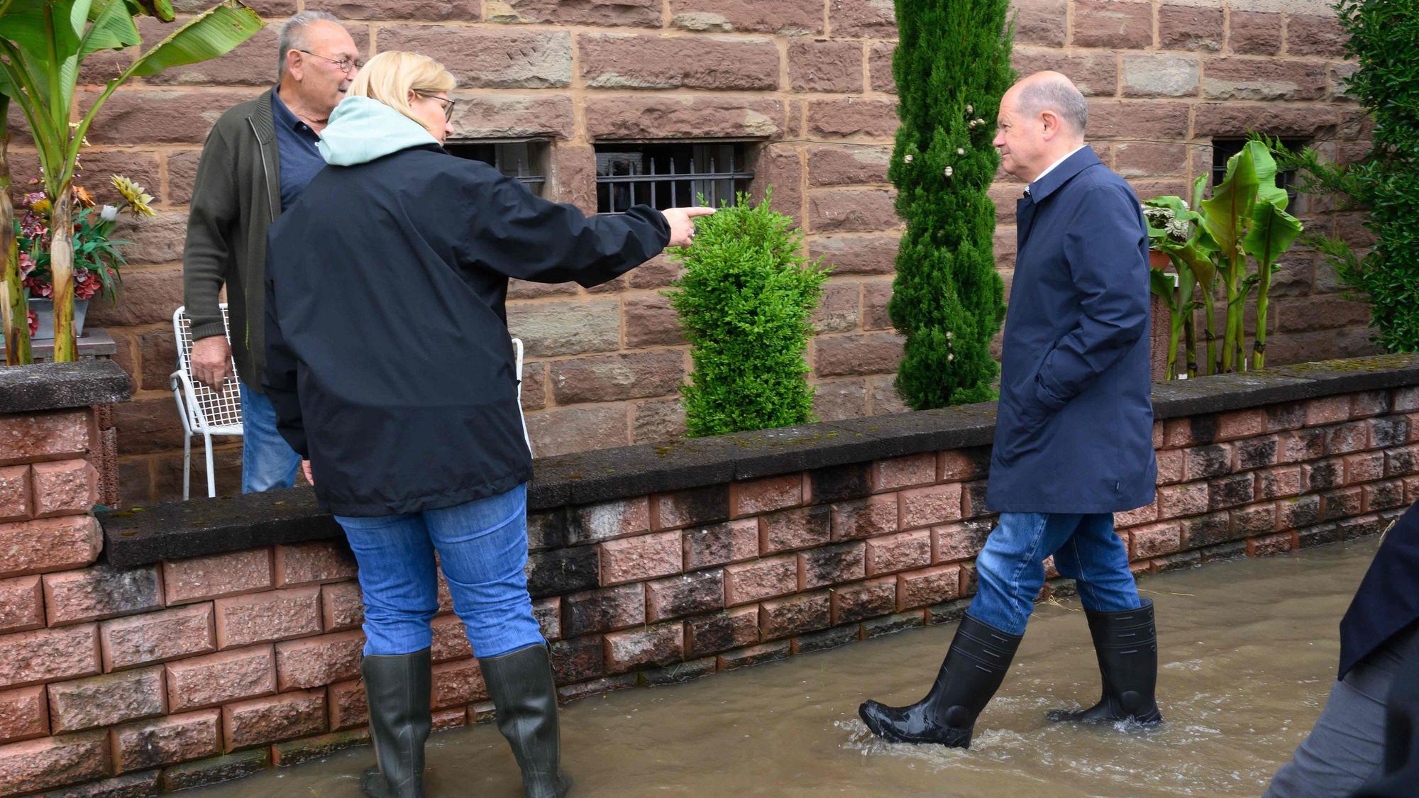 Olaf Scholz (r.) und Anke Rehlinger (M.) in Gummistiefeln sprechen am Samstag (18. Mai) in Kleinblittersdorf mit Anwohnern, die vom Hochwasser betroffen sind.