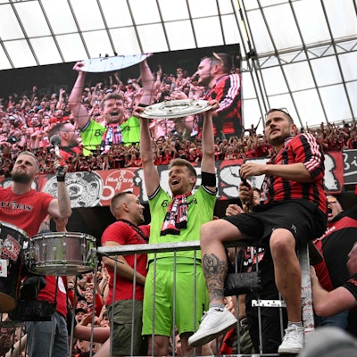 Bayer Leverkusen's Finnish goalkeeper #01 Lukas Hradecky celebrates with the Bundesliga trophy amongst the fans after the German first division Bundesliga football match between Bayer 04 Leverkusen and FC Augsburg in Leverkusen, western Germany on May 18, 2024. (Photo by INA FASSBENDER / AFP) / DFL REGULATIONS PROHIBIT ANY USE OF PHOTOGRAPHS AS IMAGE SEQUENCES AND/OR QUASI-VIDEO