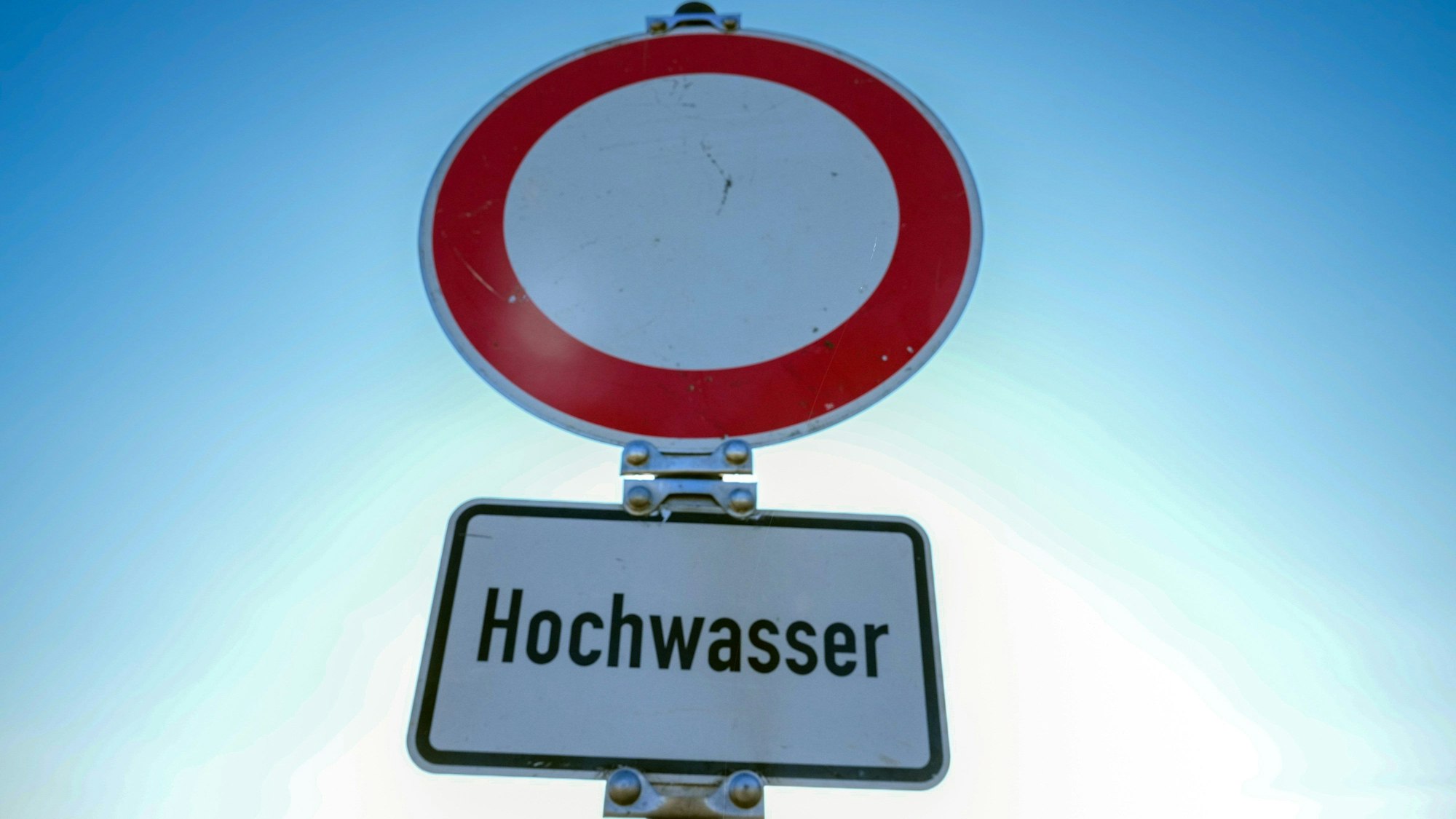 Es ist das Verkehrszeichen „Durchfahrt verboten“ zu sehen, mit einem Schild darunter, auf dem „Hochwasser“ steht.