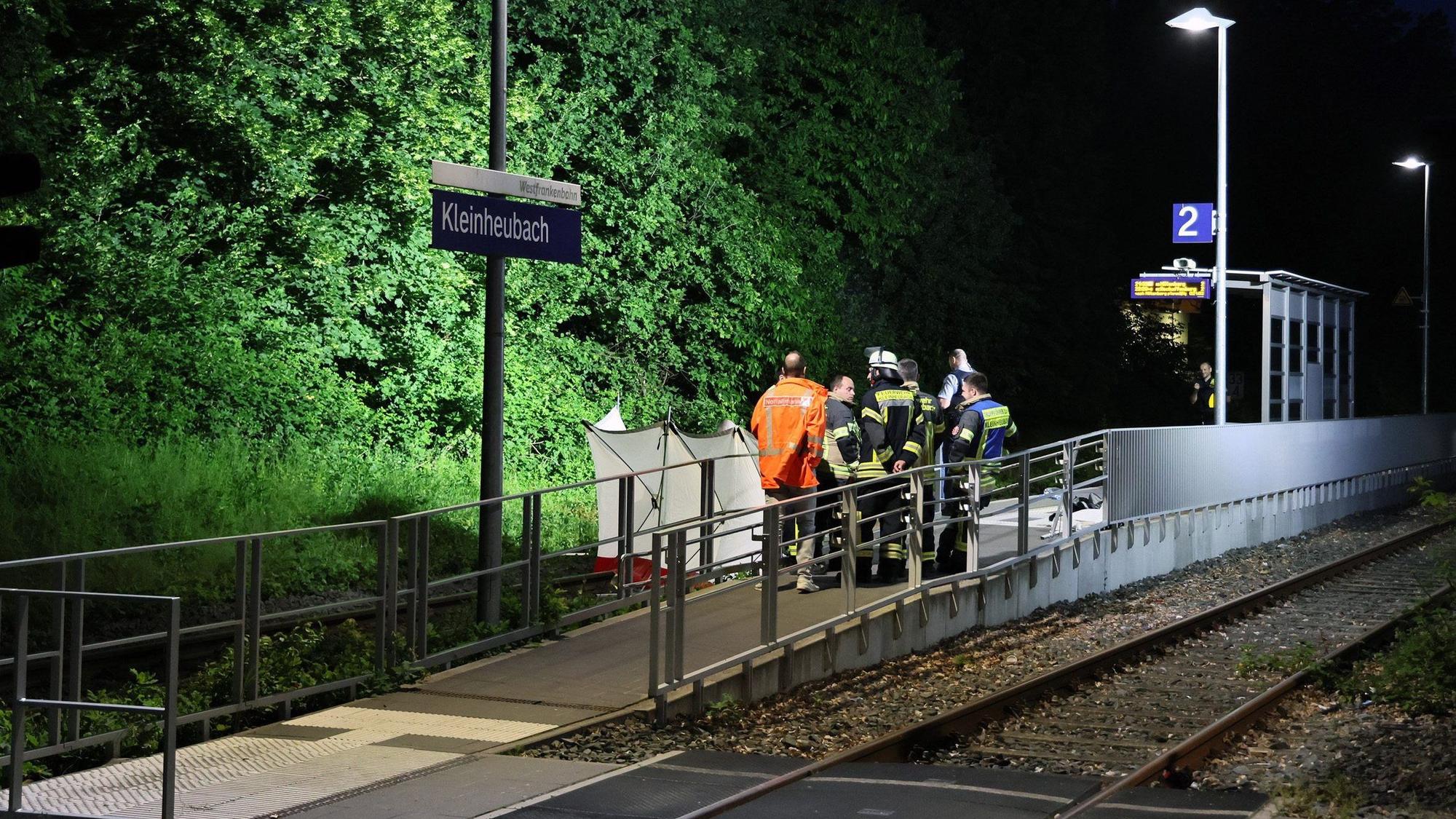 dpatopbilder - 18.05.2024, Bayern, Kleinheubach: Rettungskräfte stehen an einem Bahnsteig in Kleinheubach. Kleinheubach (dpa) - Zwei Männer sind bei einem Zugunglück in Unterfranken ums Leben gekommen. Die beiden 22- und 37-Jährigen seien am Samstagabend am Bahnhof in Kleinheubach (Landkreis Miltenberg) zwischen die Waggons eines anfahrenden Zugs geraten, dabei ins Gleisbett gefallen und tödlich verletzt worden, teilte die Polizei am Sonntag mit. Nach derzeitigem Ermittlungsstand hielten sich die Männer alleine am Bahnsteig auf. Foto: Ralf Hettler/dpa +++ dpa-Bildfunk +++