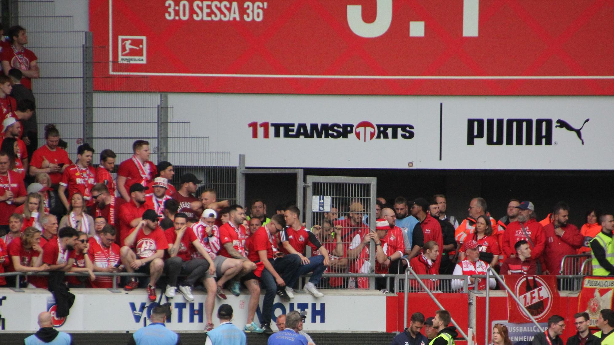 Enttäuschte Fußball-Fans sitzen auf der Brüstung der Tribüne.