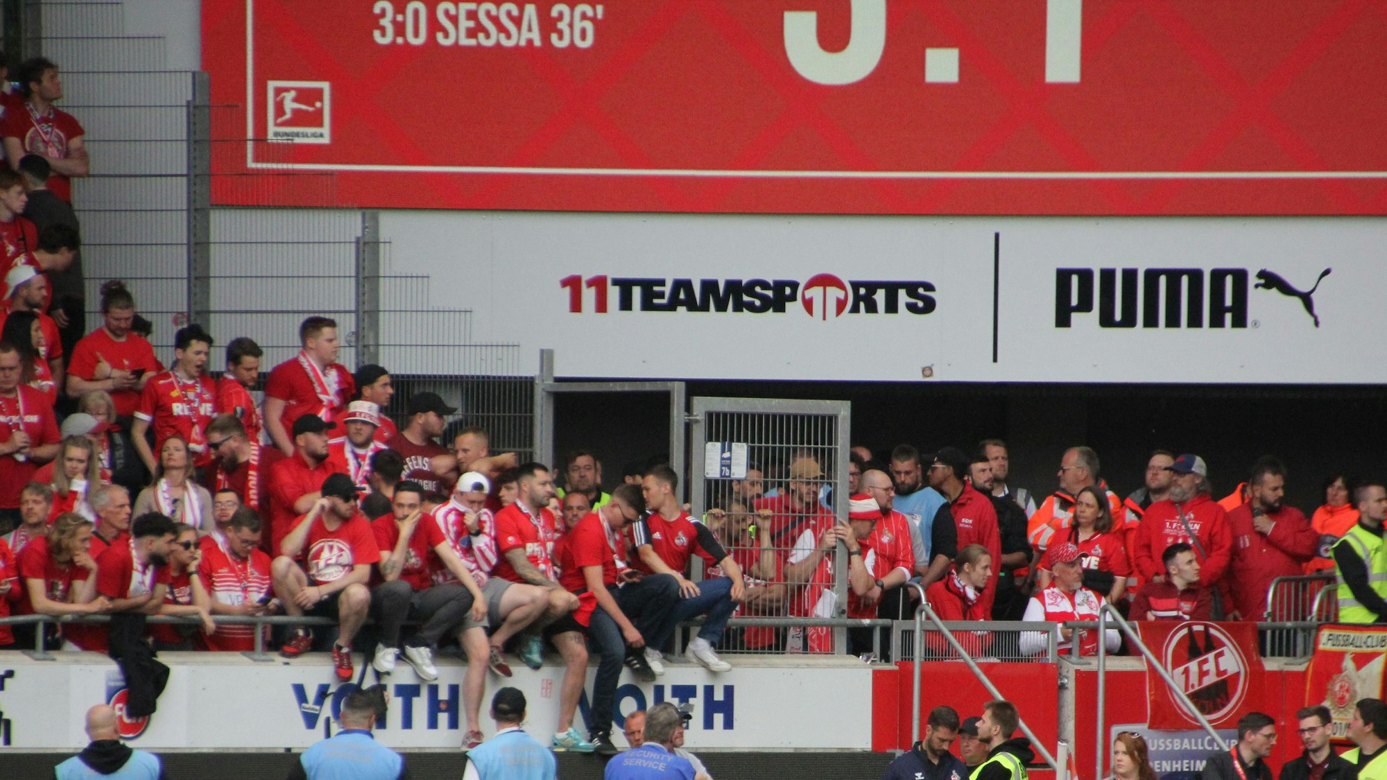 Enttäuschte Fußball-Fans sitzen auf der Brüstung der Tribüne.