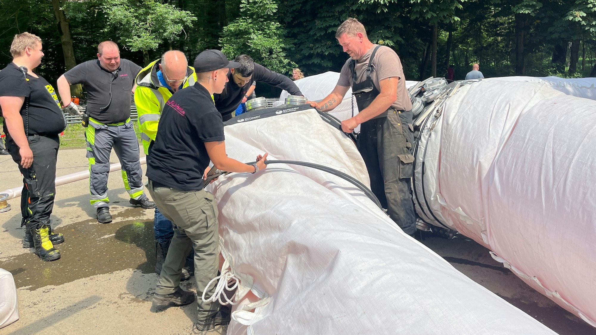 Mitarbeiterinnen und Mitarbeiter von Jola-Rent bereiten den Schlauch auf die Flutung mit Siegwasser vor.