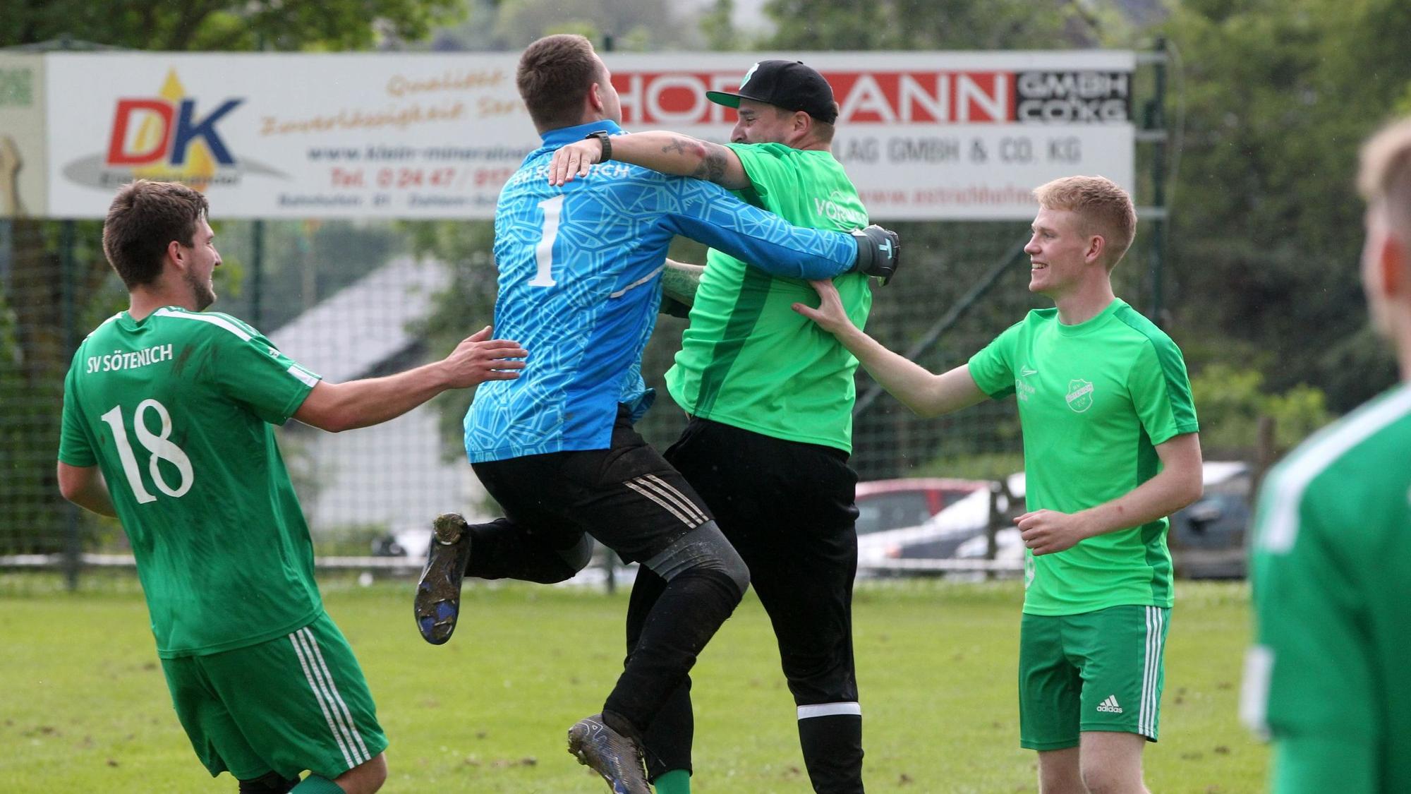 Ein Torwart springt seinem Trainer jubelnd in die Arme.