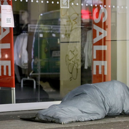 Ein Obdachloser schläft vor einem Geschäft in Köln.