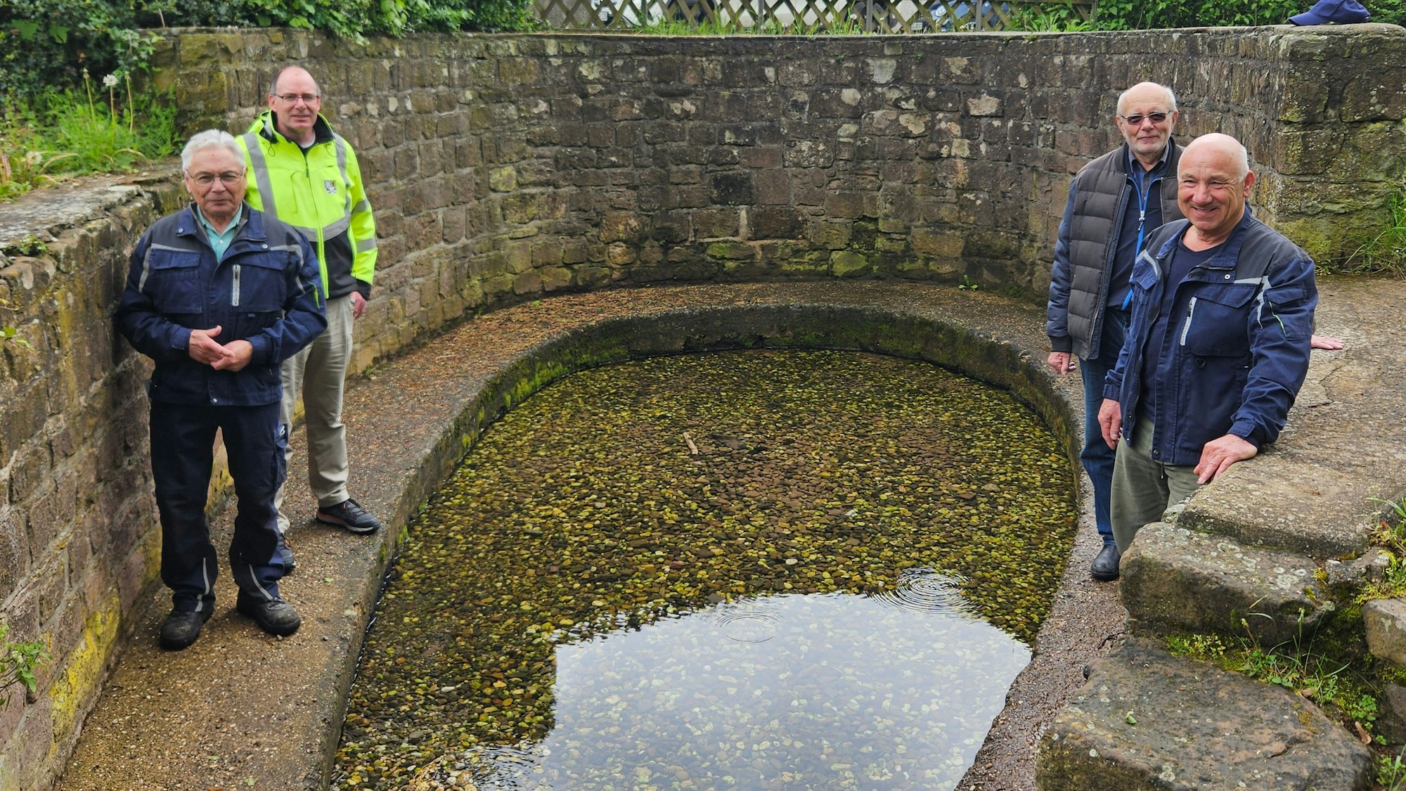 Hans Jubelius, Lothar Schatten, Hans Reiff und Peter Schildgen stehen an einem Gewässer, das von einer Mauer umgeben ist.
