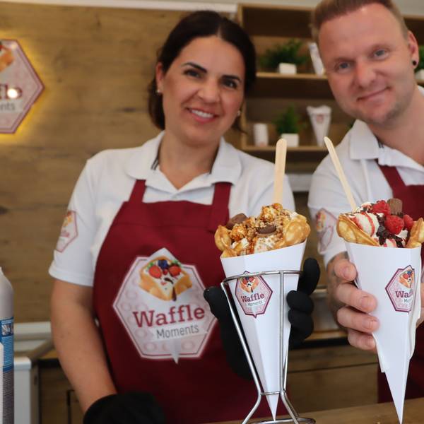 Zwei Personen in Schürzen halten gefüllte Waffeln.