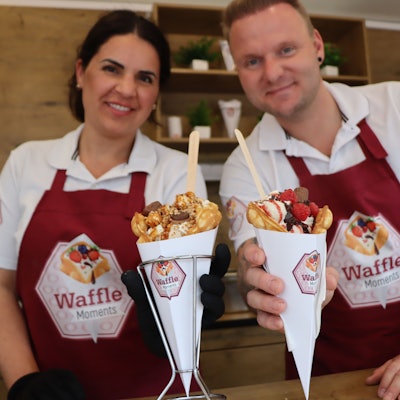 Zwei Personen in Schürzen halten gefüllte Waffeln.