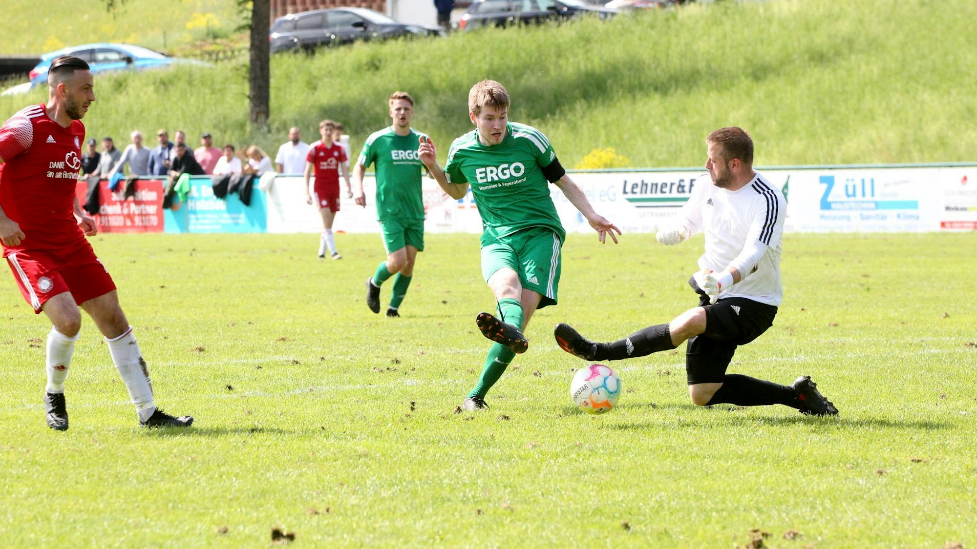Ein Sötenicher Spieler versucht den Ball unter dem ausgestreckten Bein des gegnerischen Torwarts durchzuschieben.