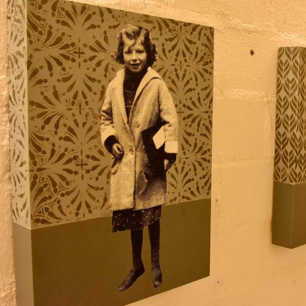 Bilder in einer Kunstausstellung. Schwarz-Weiß-Fotos von Kindern vor einem gemusterten Hintergrund.