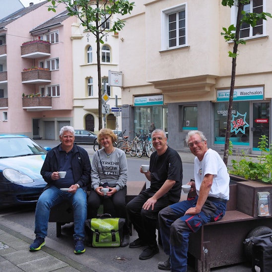 Karsten Heppner vom Bürgerverein Bayenthal-Marienburg, Sabine Müller, Matteo Specchio und Bodo Schmitt testen schon einmal das Kaffeetrinken auf Baum-Sitzbänken vor der Eisdiele.
