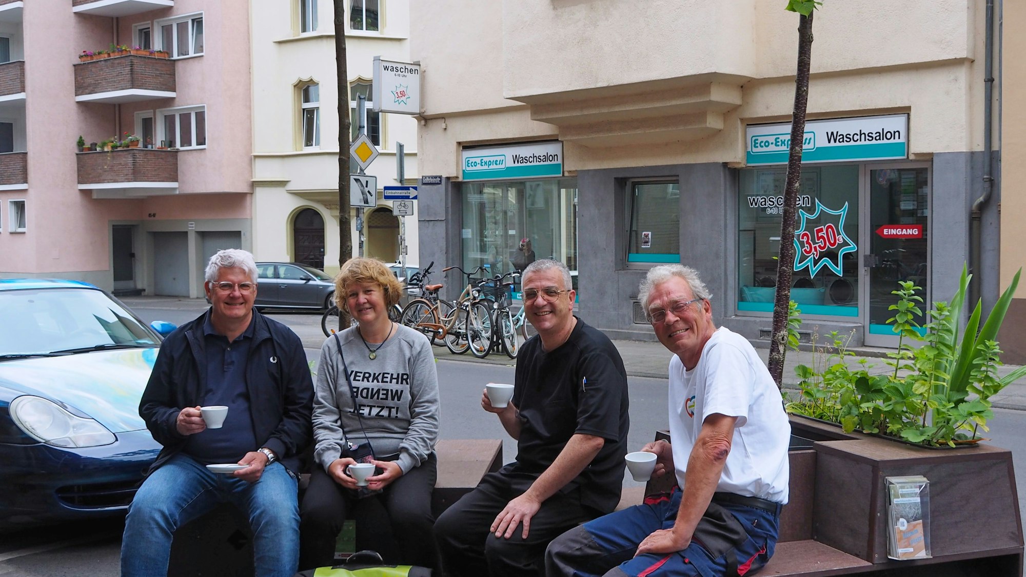 Karsten Heppner vom Bürgerverein Bayenthal-Marienburg, Sabine Müller, Matteo Specchio und Bodo Schmitt testen schon einmal das Kaffeetrinken auf Baum-Sitzbänken vor der Eisdiele.
