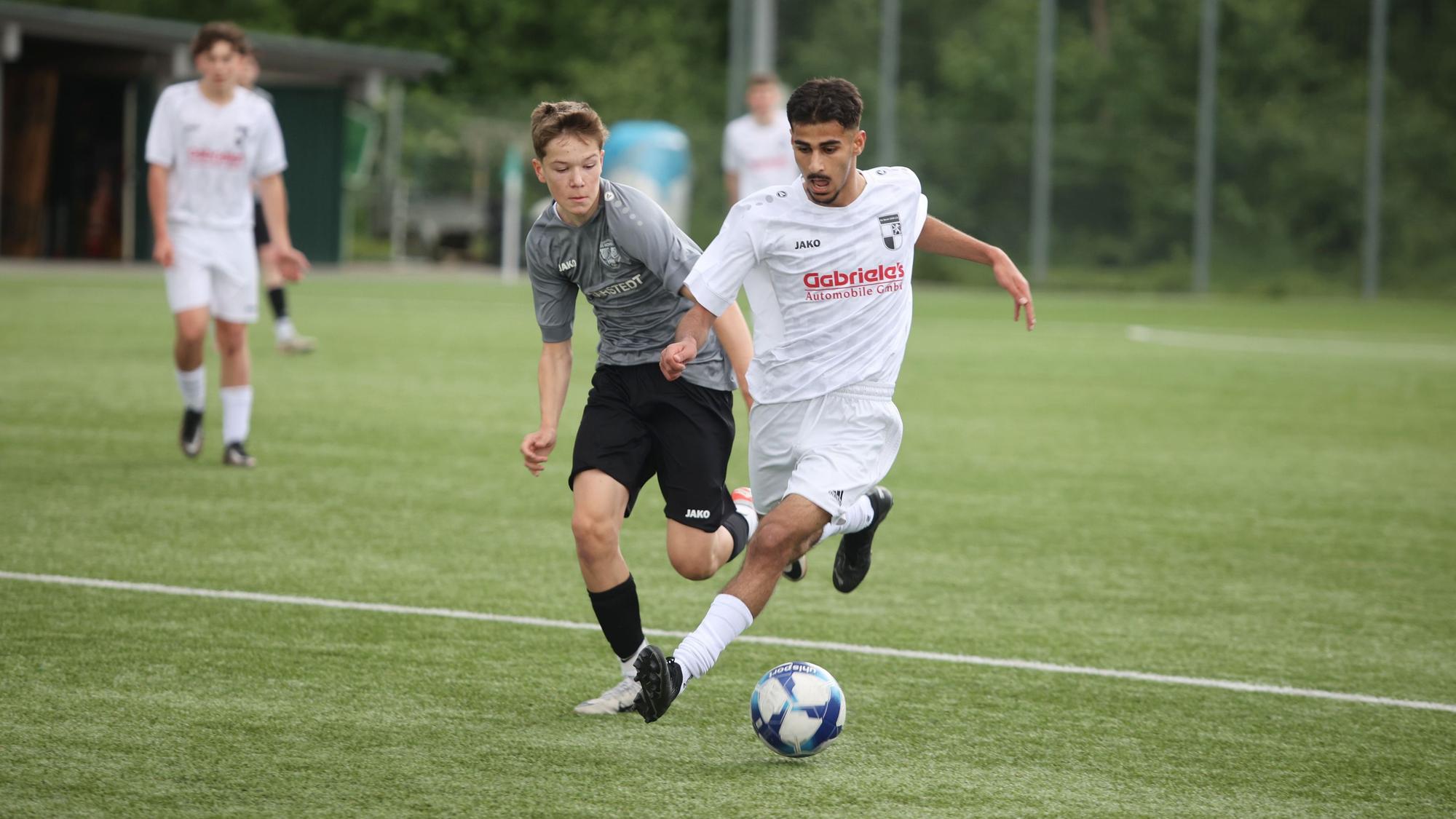 Eine Spielstation zweier Jugendteams auf einem Fußballplatz.