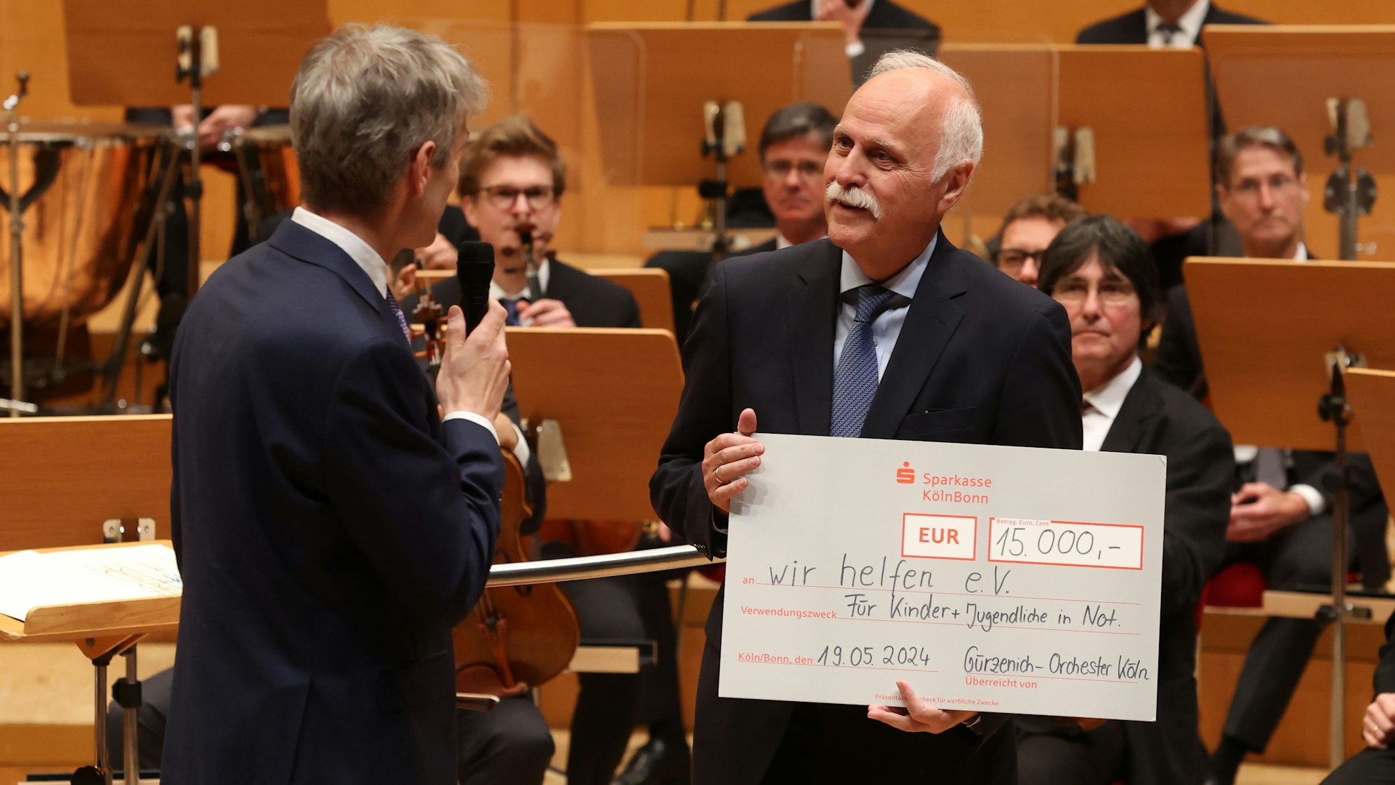 Karl-Heinz Goßmann hält einen großen Scheck in der Hand und freut sich darüber.