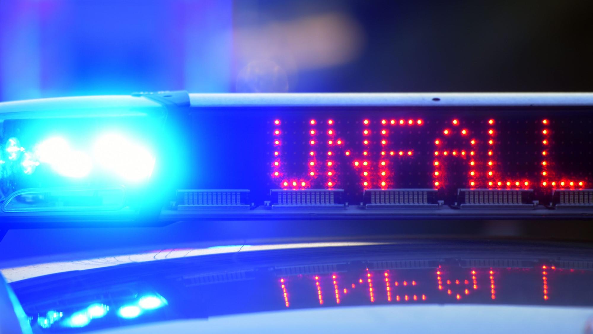 Das Wort „Unfall“ steht auf einem Polizeiauto neben Blaulicht.