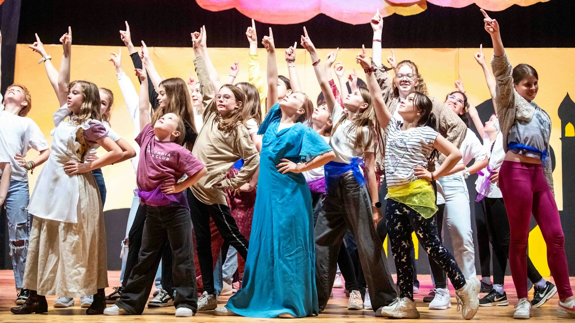 Das Bild zeigt eine Gruppe von Schülerinnen, die nach dem letzten Akkord ihren rechten Arm in Richtung Himmel strecken.