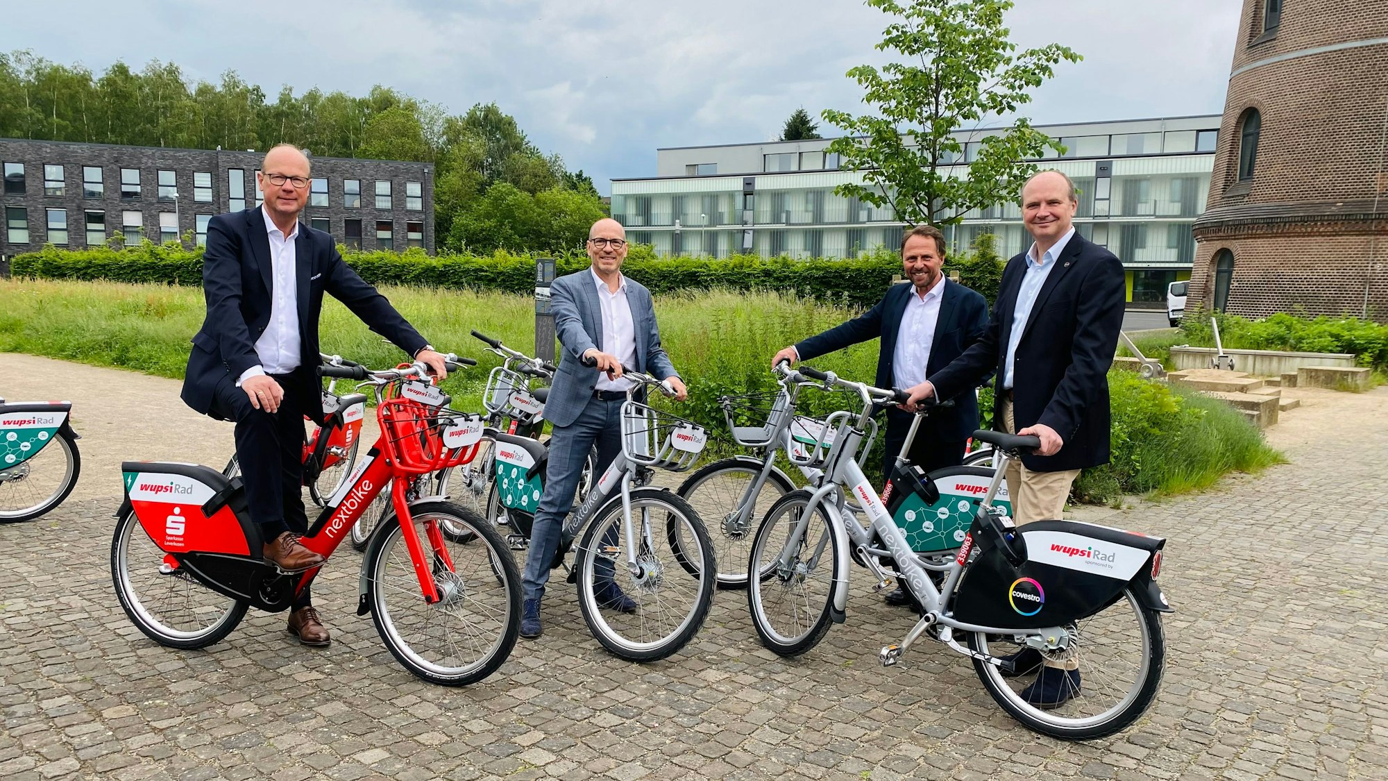 Markus Grawe von der Sparkasse Leverkusen, Wupsi-Geschäftsführer Marc Kretkowski, Oberbürgermeister Uwe Richrath und Daniel Koch von Covestro stehen nebeneinander. Alle haben ein Wupsirad neben sich stehen.