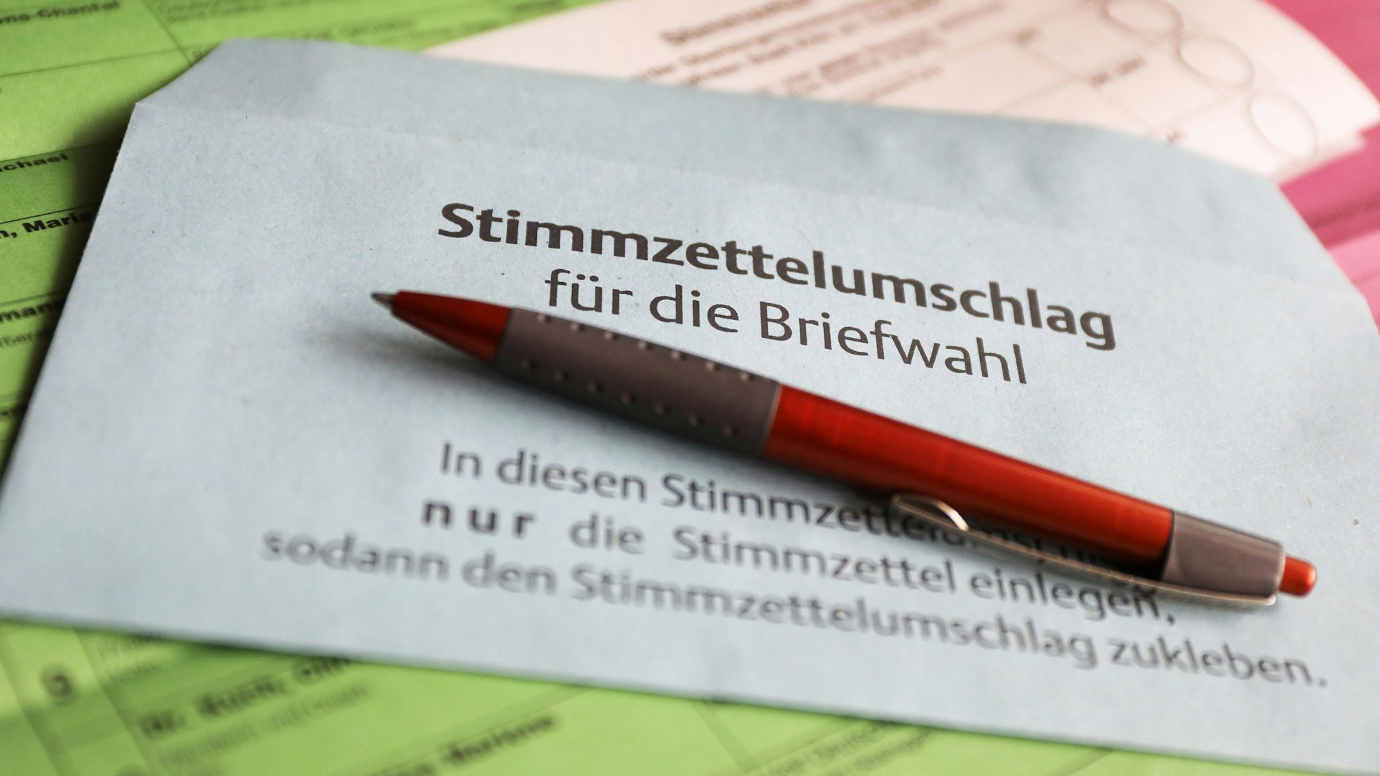 Ein Stimmzettel und ein Umschlag für die Briefwahl liegen auf dem Tisch.