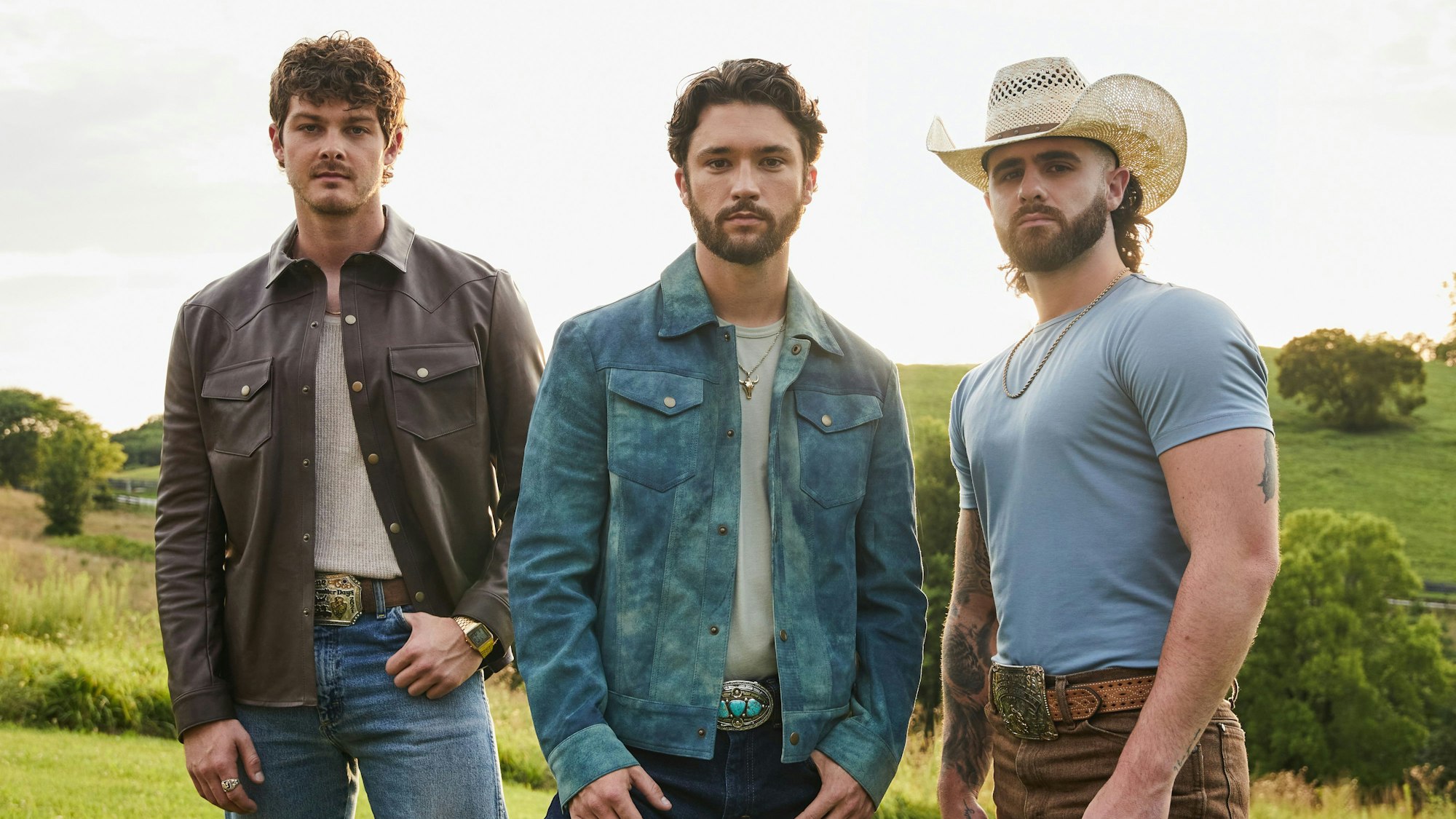 Drei Männer im Cowboyoutfit stehen auf einer Wiese