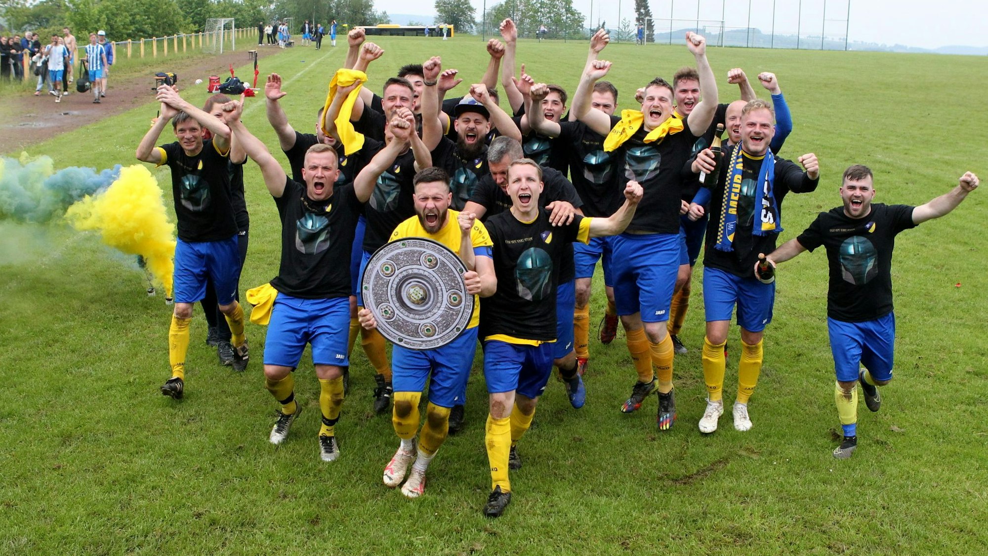 Ein Team feiert mit einer Meisterschale den Aufstieg.