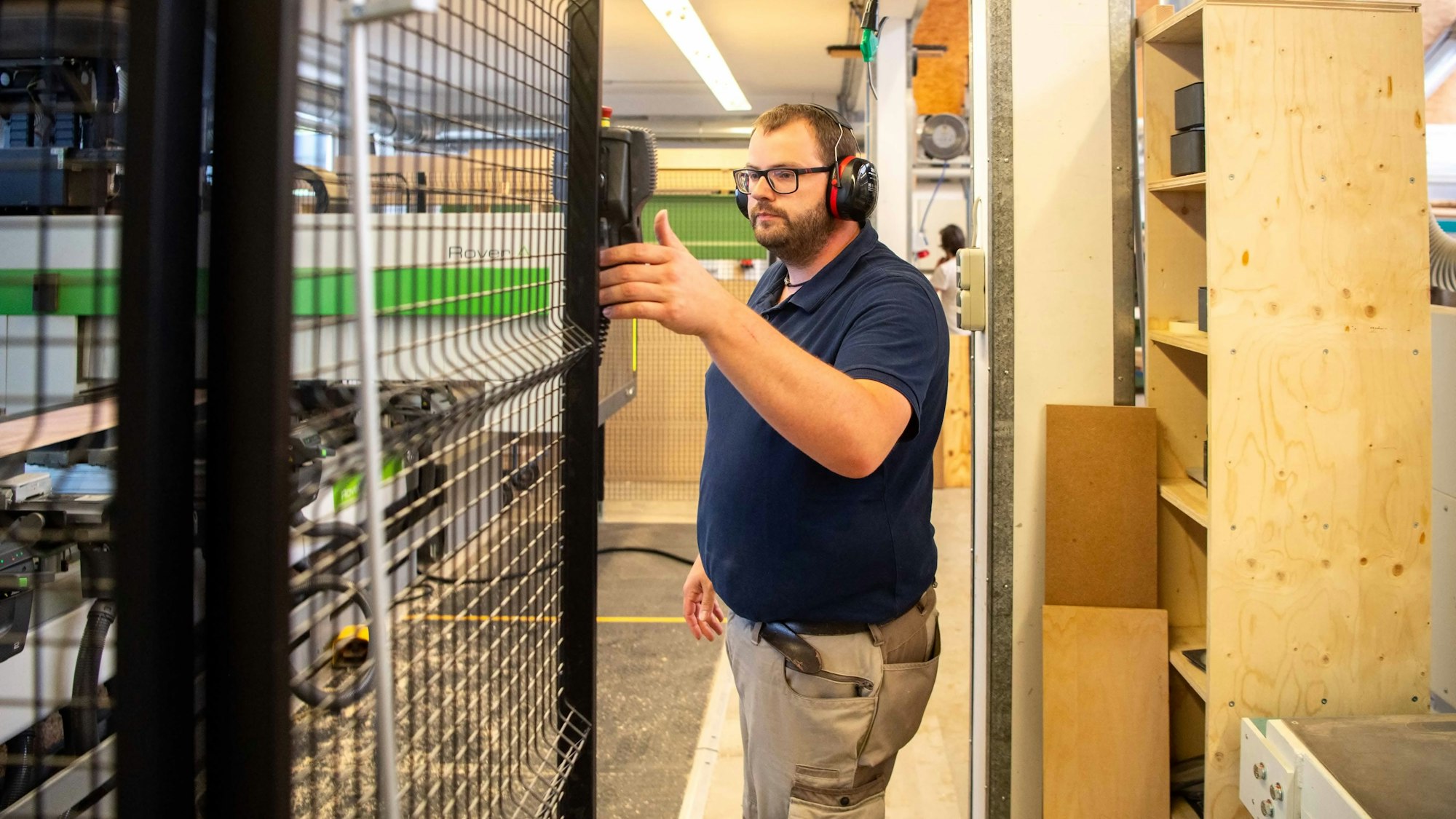 Das Bild zeigt Stefan Schlengel, wie er die CNC-Holzfräse bedient.