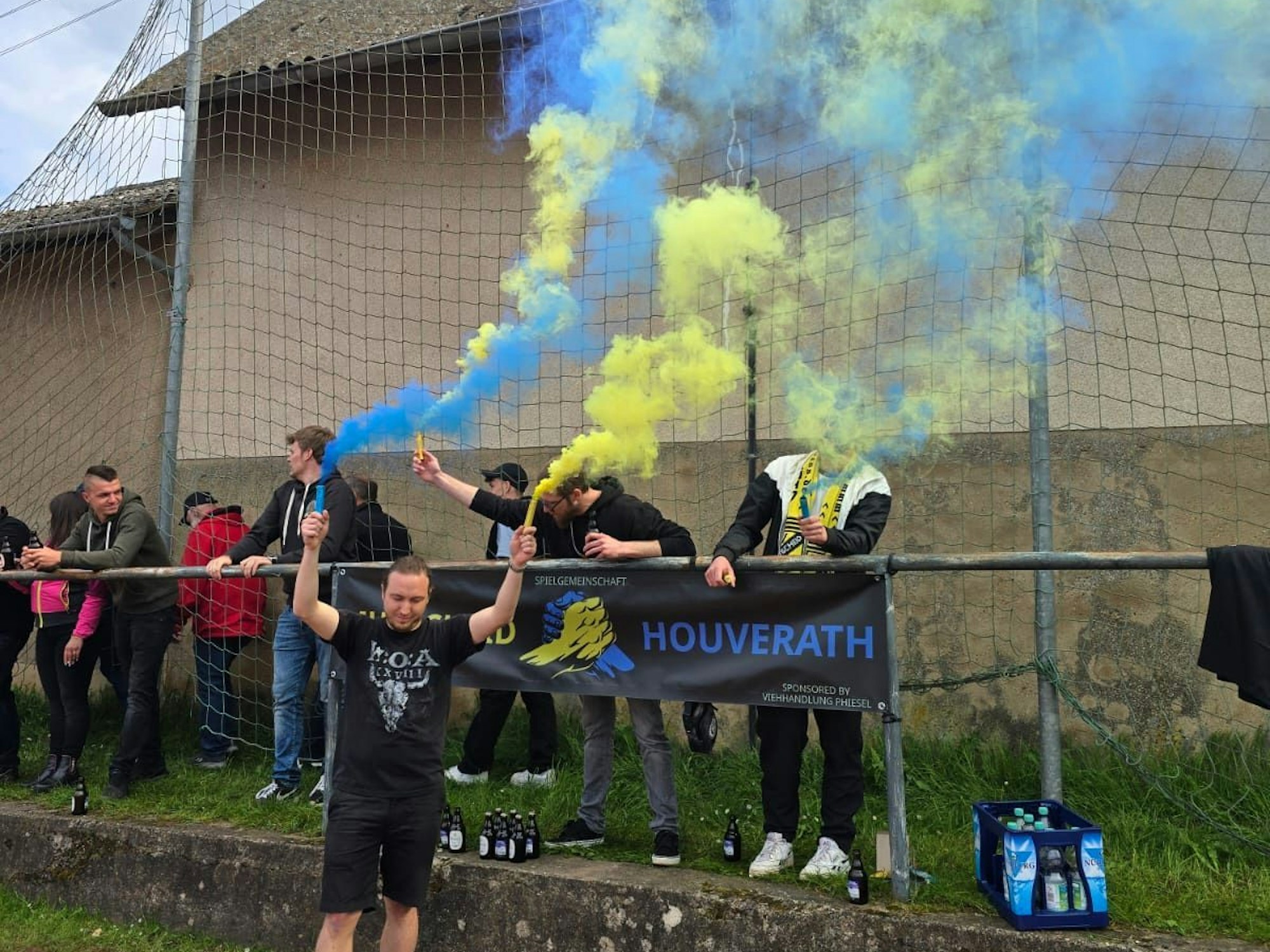 Ein Fan feiert den Klassenerhalt mit gelben und blauen Rauchfackeln.