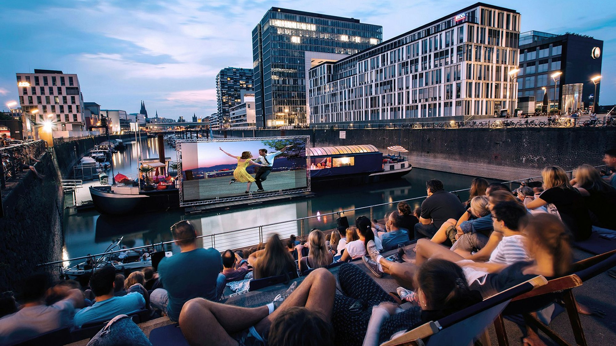 Menschen sitzen auf den Treppen im Rheinauhafen