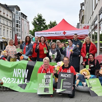 Mit Plakaten und einem großen Banner in der Hand haben sich Erzieherinnen und Erzieher für das Foto aufgestellt.