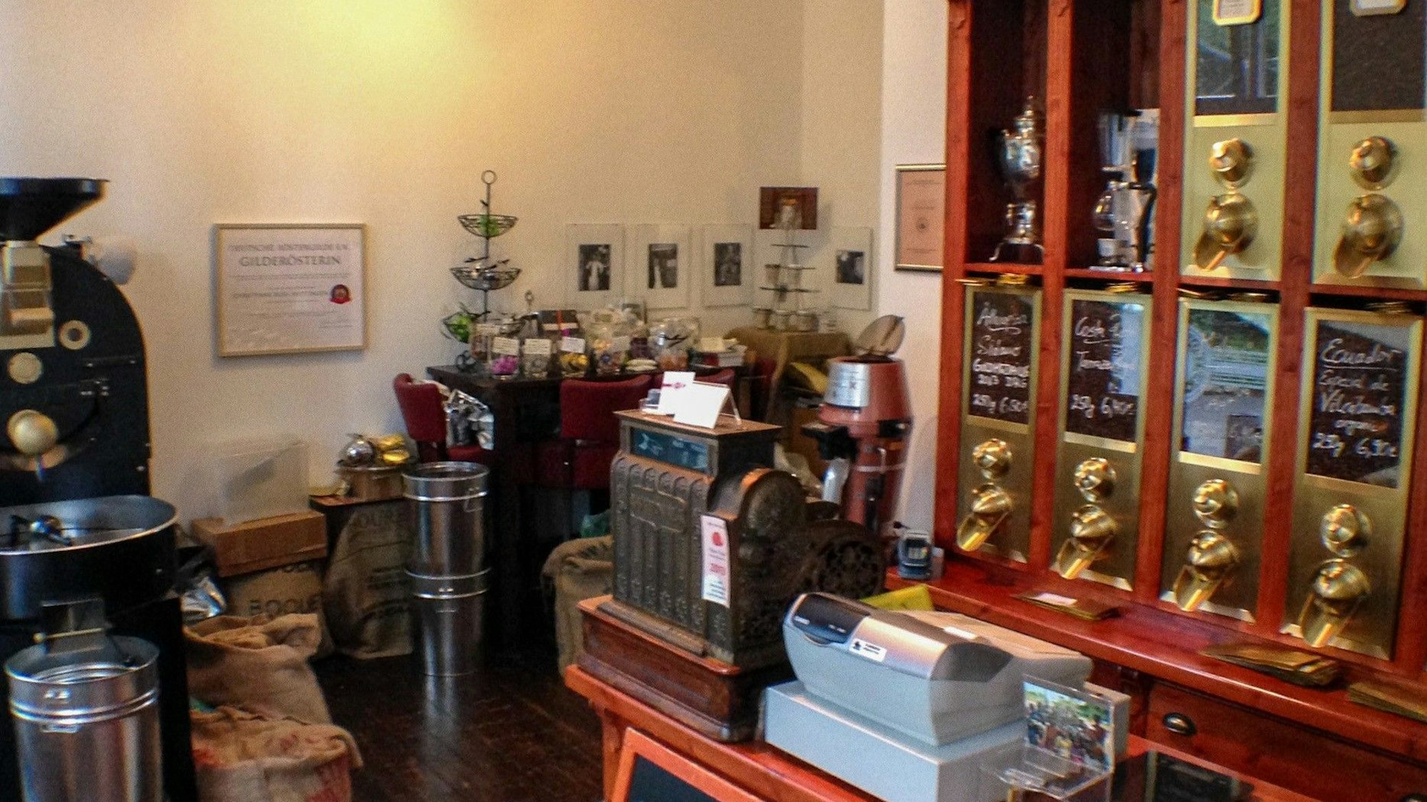 Eine Röstmaschine, eine Kasse, hinter der Kasse Kaffeeschütten.