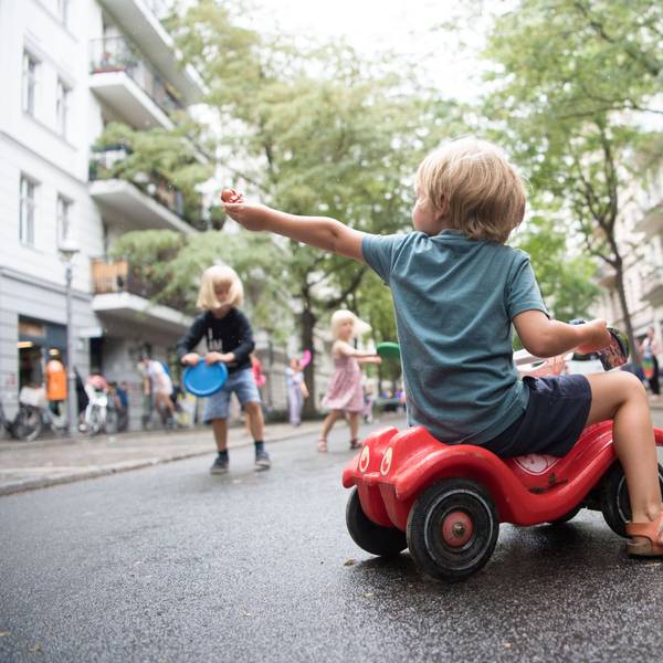 Ein Junge sitzt auf einem Bobbycar. Kinder spielen auf der ersten temporären Spielstraße in Berlin.