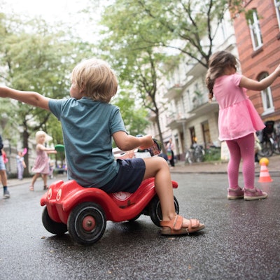 Ein Junge sitzt auf einem Bobbycar. Kinder spielen auf der ersten temporären Spielstraße in Berlin.