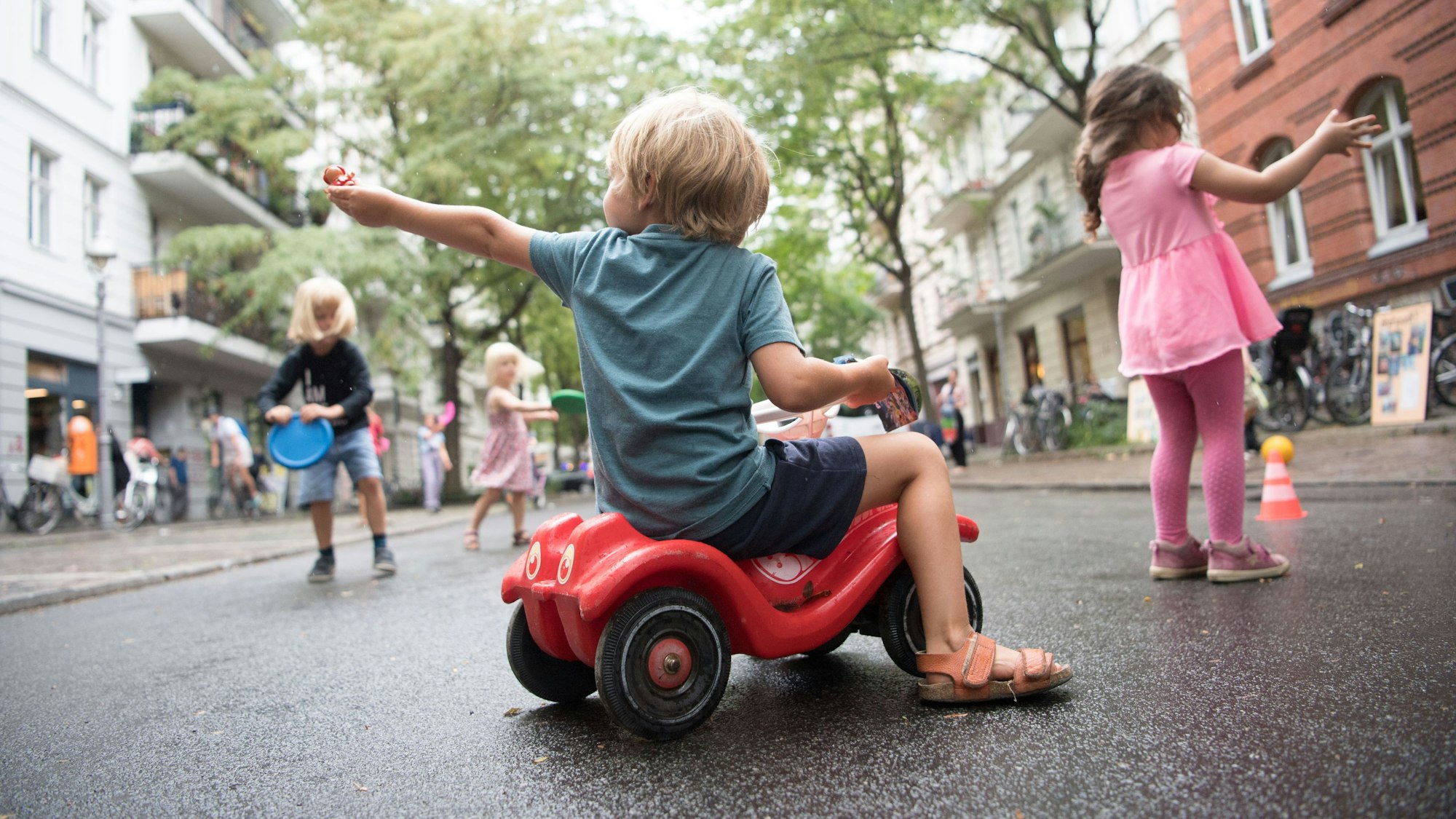 Ein Junge sitzt auf einem Bobbycar. Kinder spielen auf der ersten temporären Spielstraße in Berlin.