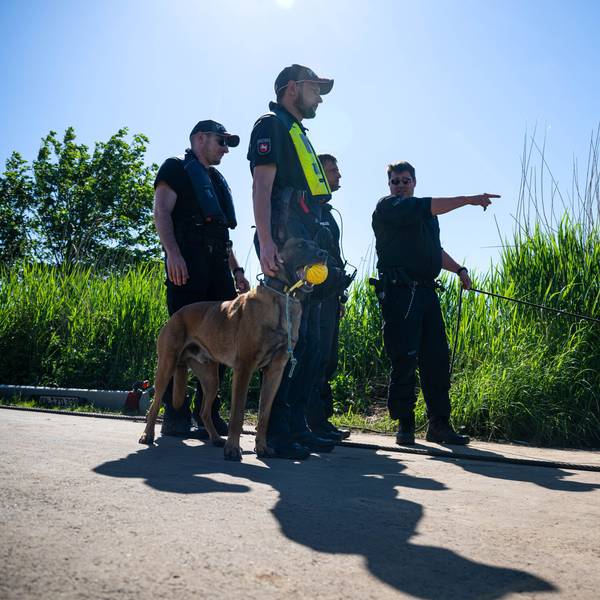Einsatzkräfte der Polizei stehen bei der Suche nach dem vermissten Arian mit einem Spürhund an der Oste.