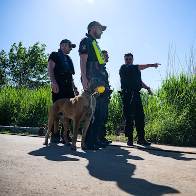 Einsatzkräfte der Polizei stehen bei der Suche nach dem vermissten Arian mit einem Spürhund an der Oste.
