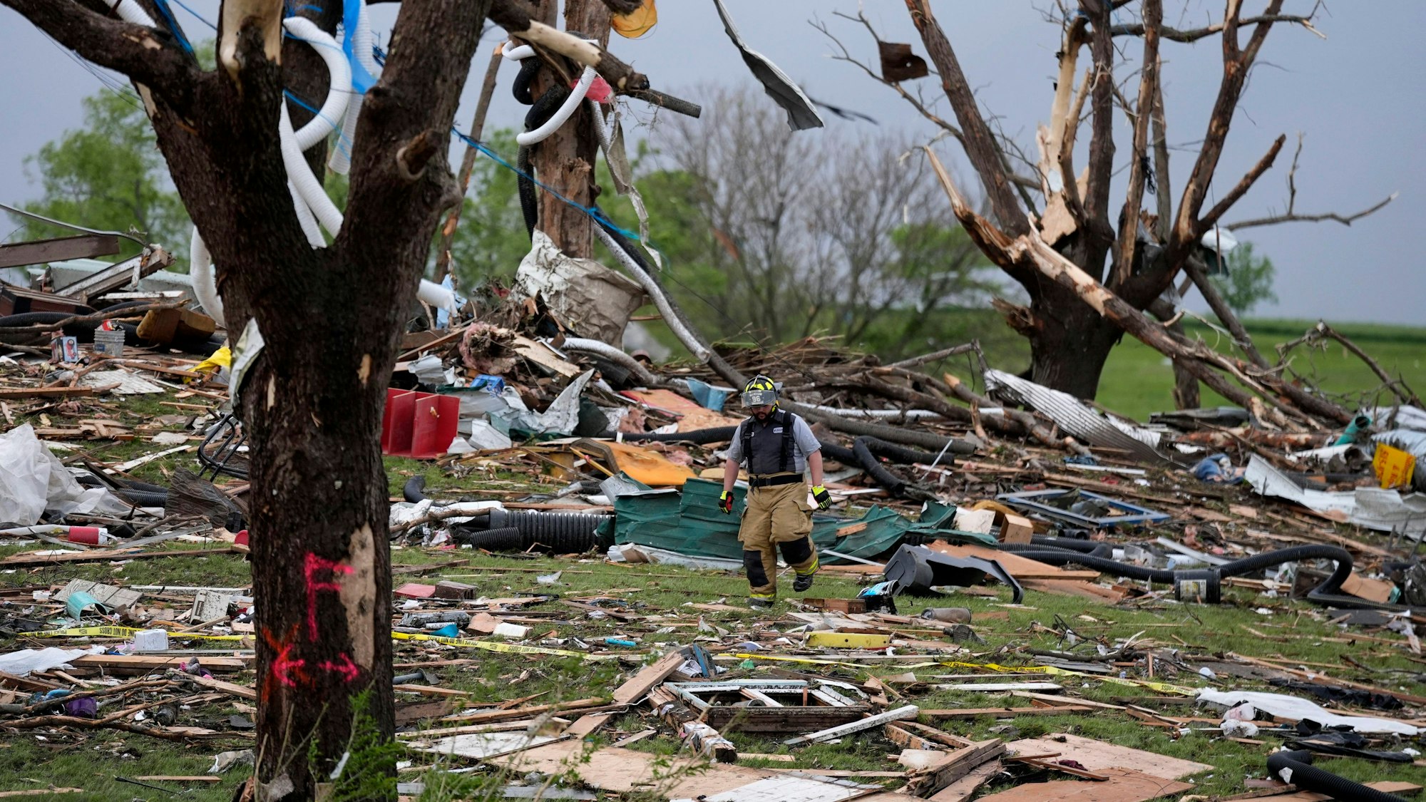 Ein Feuerwehrmann geht in Greenfield, Iowa, zwischen von einem Tornado zerstörten Häusern umher.