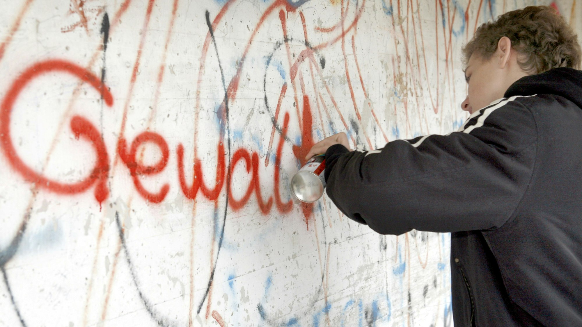 Ein 14-jähriger Jugendlicher sprüht mit roter Farbe aus der Spraydose das Wort "Gewalt" an eine schon beschmierte Wand in Lichtenfels.