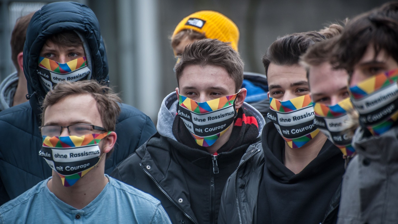 Schüler des Berufskollegs in Leverkusen-Opladen tragen eine bunte Maske mit der Aufschrift„ Schule ohne Rassismus. Schule mit Courage.“