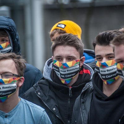 Schüler des Berufskollegs in Leverkusen-Opladen tragen eine bunte Maske mit der Aufschrift„ Schule ohne Rassismus. Schule mit Courage.“