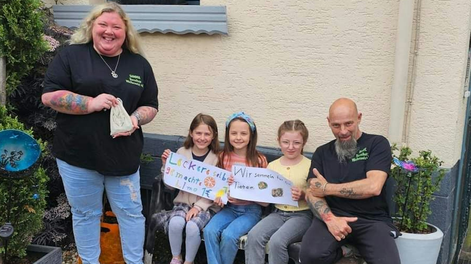 Drei Mädchen sitzen auf der Bank und halten Plakate hoch. Darauf steht: „Leckere selbst gemachte Limo“ und „Wir sammeln für ein Tierheim“. Flankiert werden sie von Sandra und Marc Fritzler von der Tierhilfe Weilerswist.
