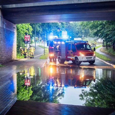 Das Bild zeigt die überflutete Unterführung. Im Hintergrund stehen zwei Feuerwehrfahrzeuge.
