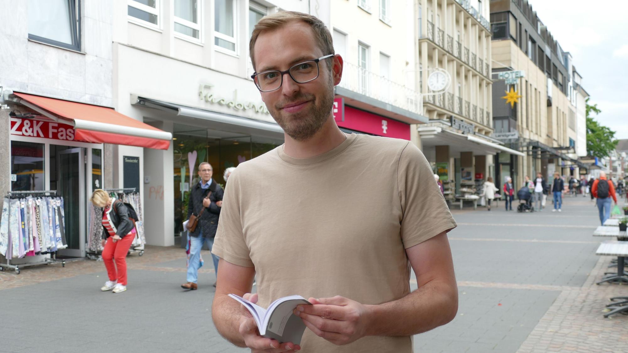 Ein Mann hält ein Grundgesetz in der Hand.