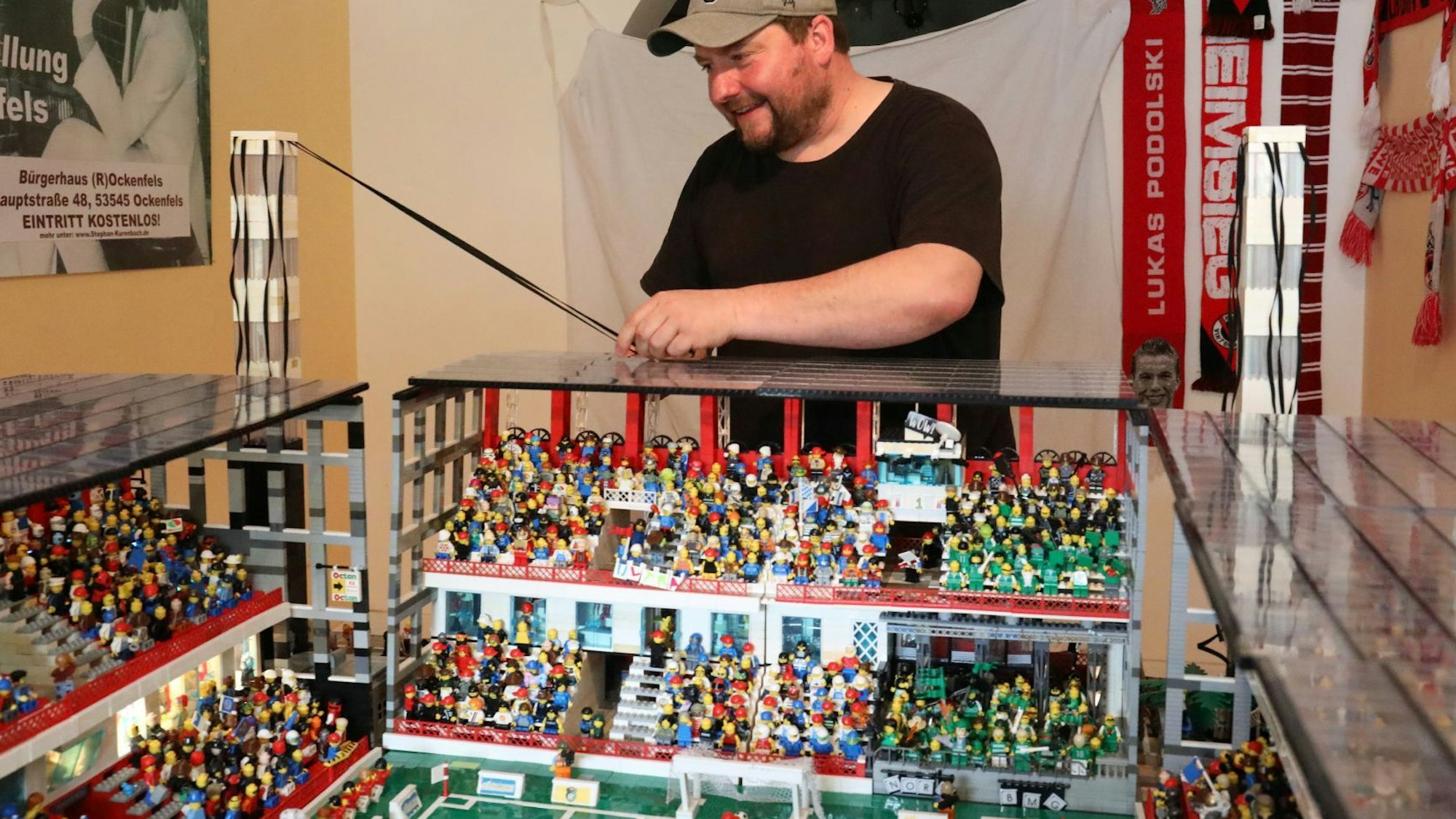 Ein Mann mit Basecap vor dem Modell des Kölner Stadions.