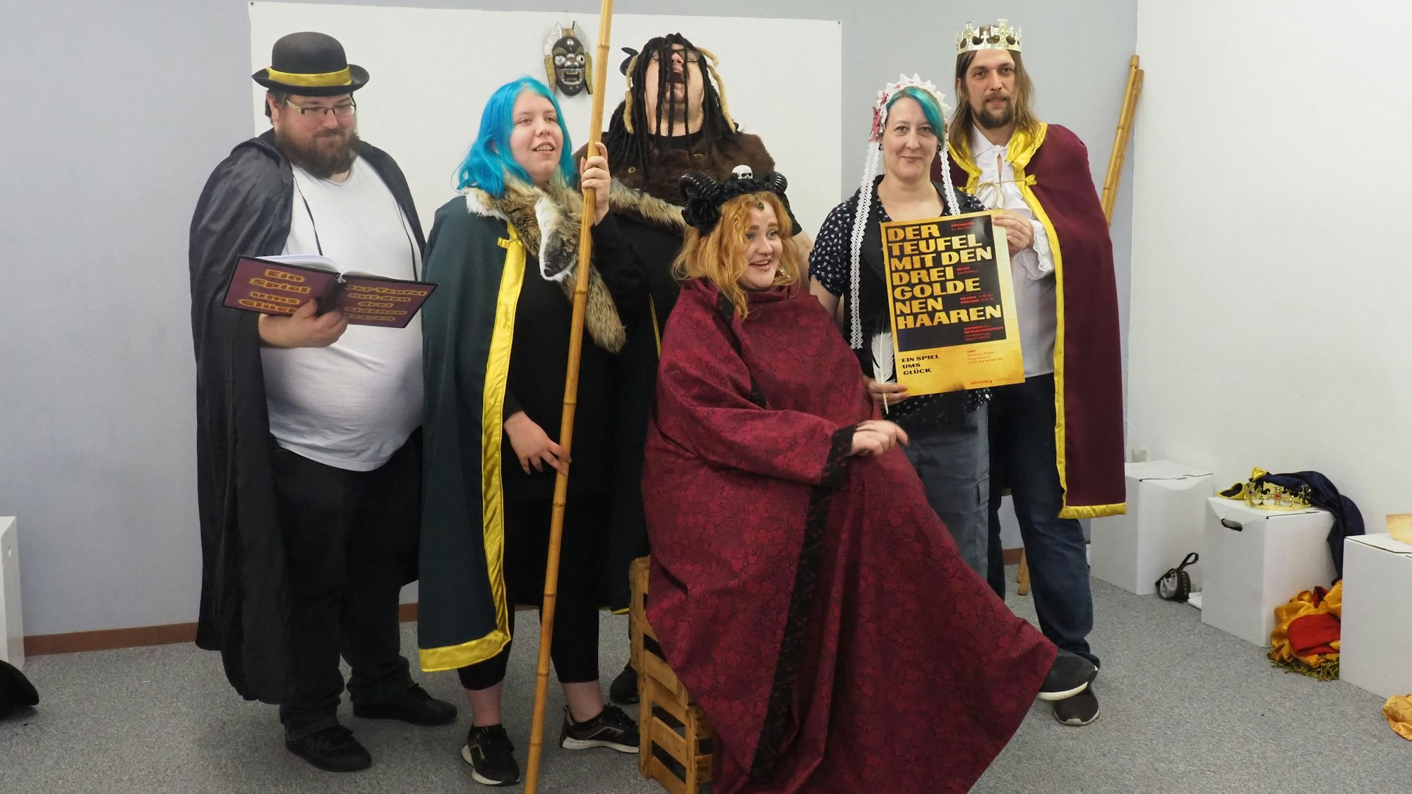 Sechs junge Erwachsene in Kostümen spielen Theater.