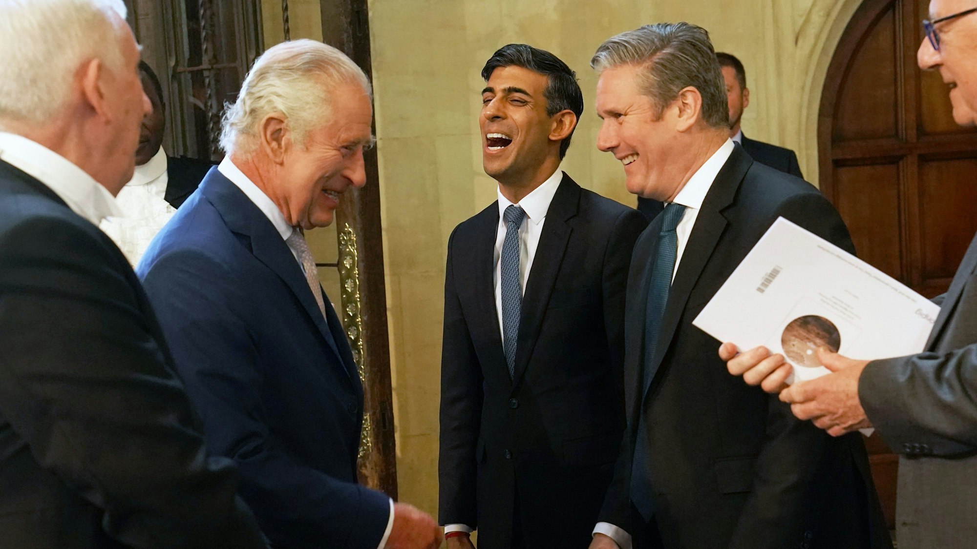 Rishi Sunak lacht zwischen Politikern.