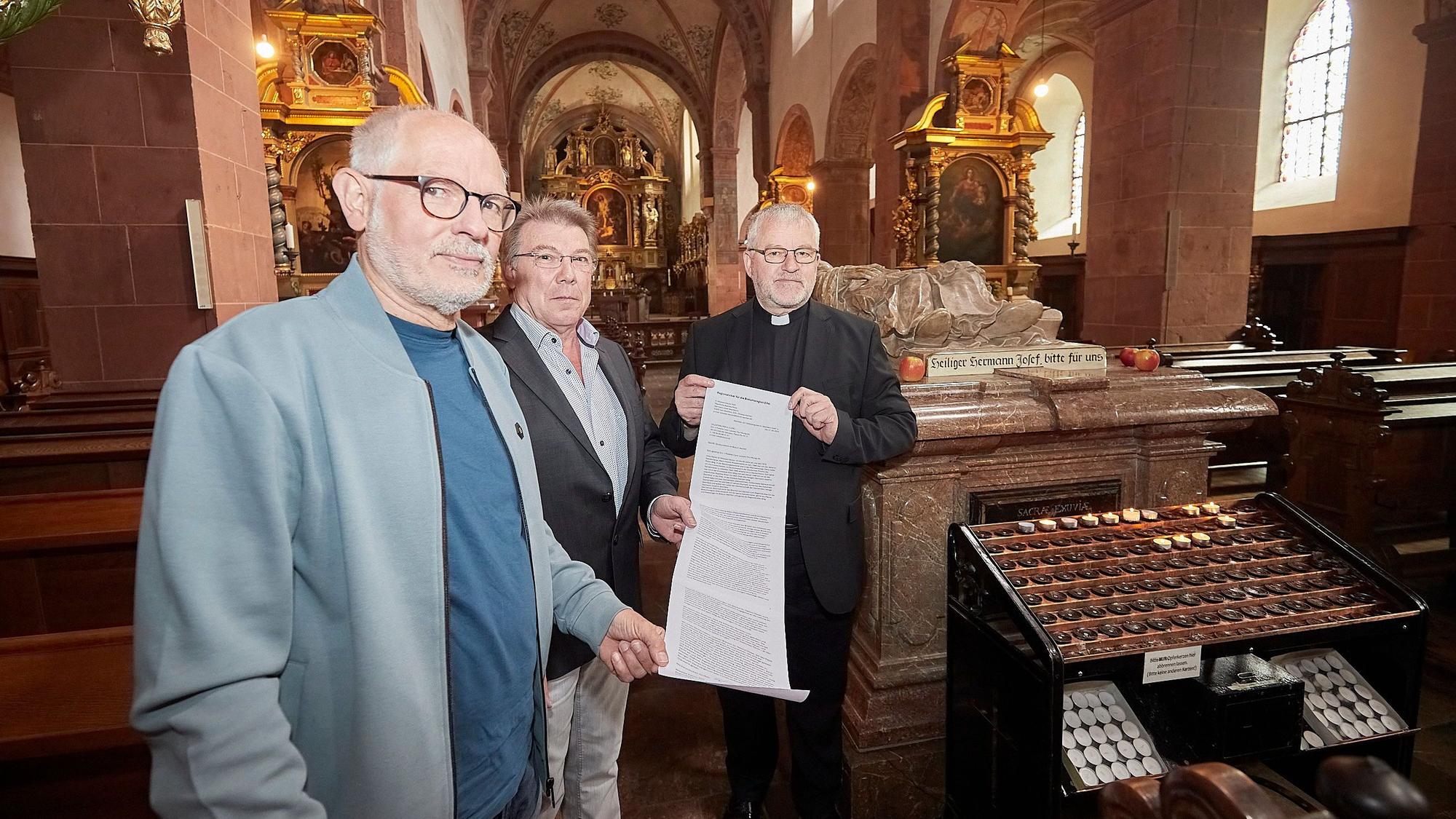 Drei Mitglieder des Regionalteams stehen in der Basilika Steinfeld und halten einen Brief in der Hand, den sie an den Vatikan schicken.