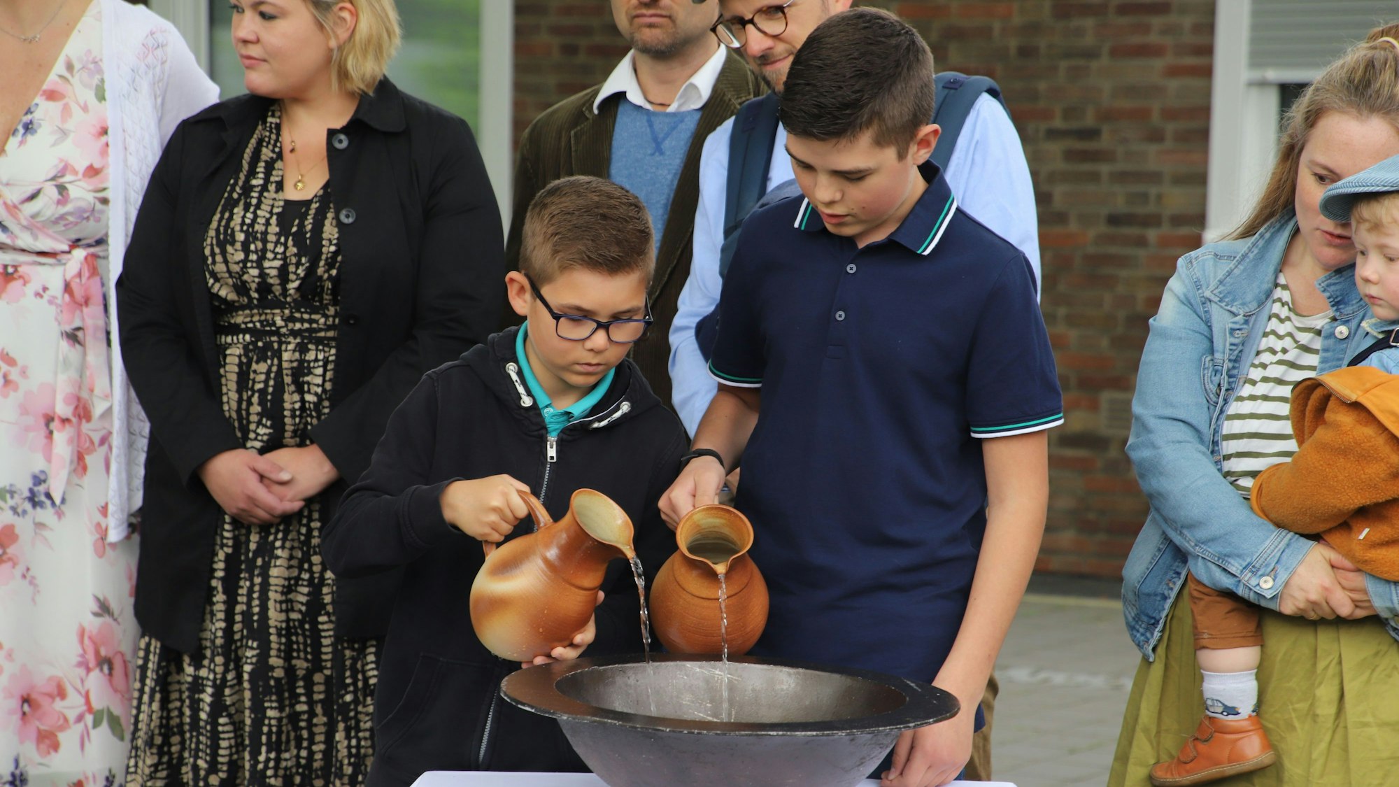 Julian (l.) und Max gießen das Wasser in das Taufbecken.