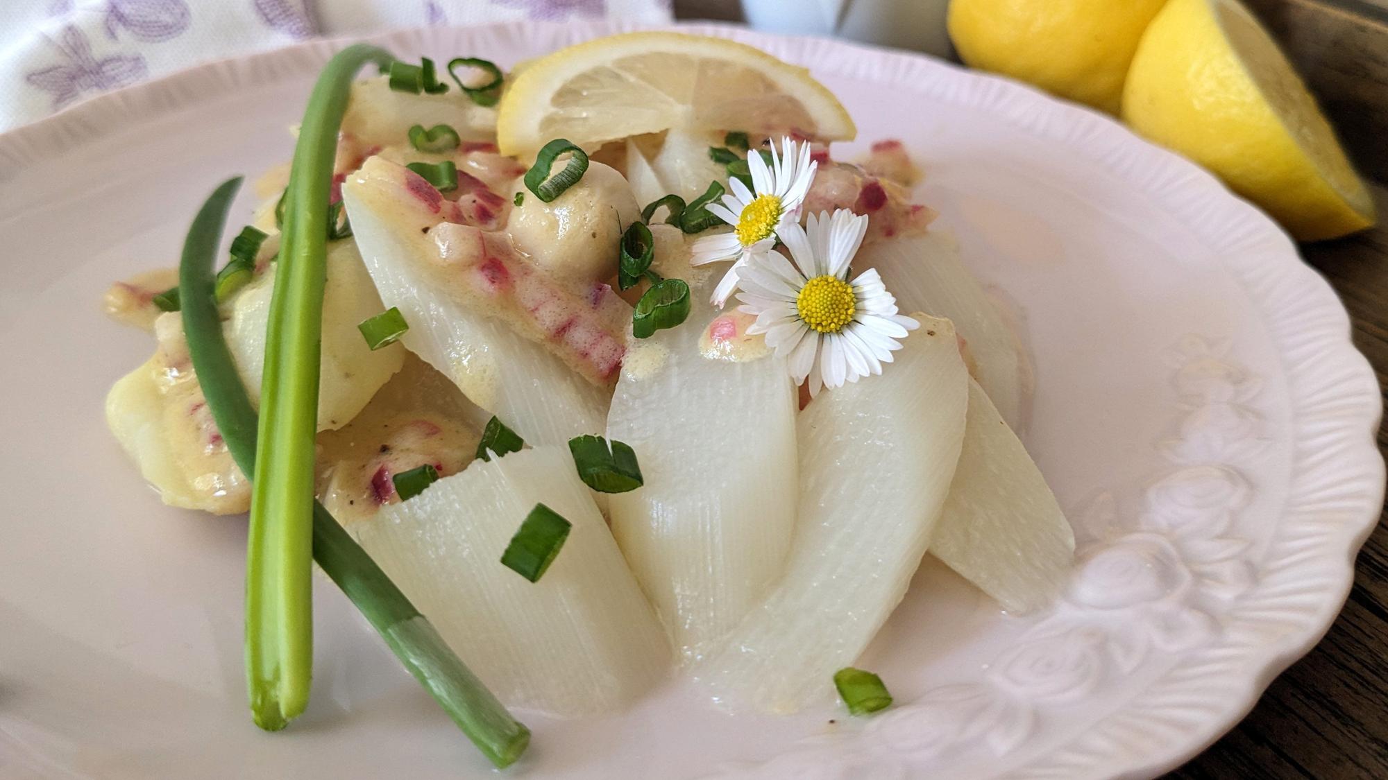 Rote Zwiebelwürfelchen und Gänseblümchen verpassen dem Spargelsalat mit erfrischender Zitrusnote ein paar frühsommerliche Farbtupfer.